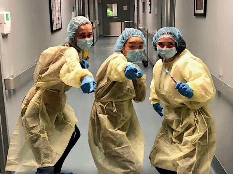 在医院的走廊里，三名穿着外科手术服的年轻女子指着观众