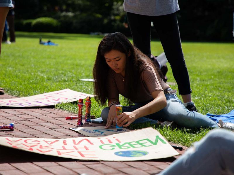 在一个阳光明媚的日子里，一名年轻女子正在为气候游行制作海报