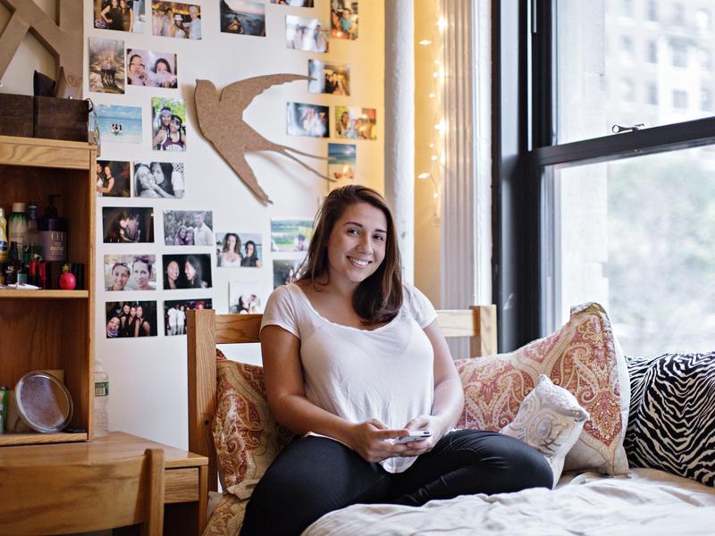 student relaxes on her bed in her dorm room